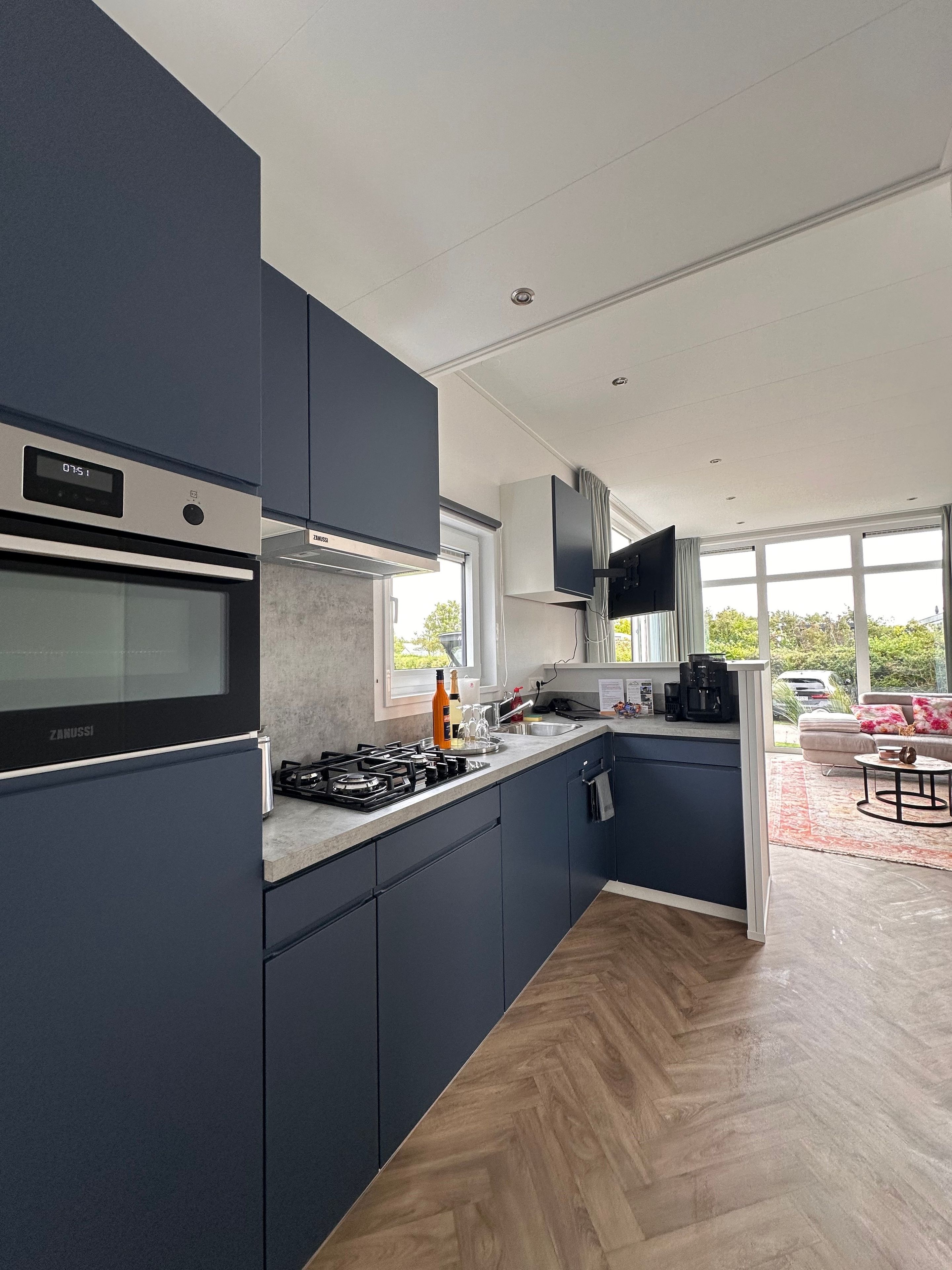 Una cocina moderna con electrodomésticos integrados, un comedor con sofá y ventanas amplias.