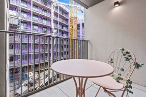 A balcony with a table and chairs, overlooking a construction site with a purple building and a yellow crane. - #20 LuxDigbeth Apt|near Hippodrome Square|Sleeps 6 (Deritend)