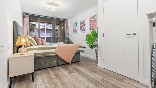 A modern bedroom with a bed, bedside table, lamp, and large windows. - #20 LuxDigbeth Apt|near Hippodrome Square|Sleeps 6 (Deritend)