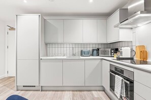 A modern kitchen with white cabinetry, a built-in oven, and a microwave. - #20 LuxDigbeth Apt|near Hippodrome Square|Sleeps 6 (Deritend)