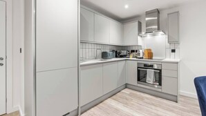 A modern kitchen with white cabinetry, a built-in oven, and a microwave. - #20 LuxDigbeth Apt|near Hippodrome Square|Sleeps 6 (Deritend)