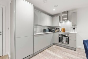 A modern kitchen with white cabinetry, a built-in oven, and a microwave. - #20 LuxDigbeth Apt|near Hippodrome Square|Sleeps 6 (Deritend)