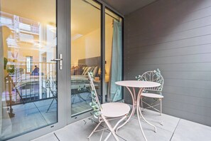 A balcony with a glass door, a white table, and a chair. - #20 LuxDigbeth Apt|near Hippodrome Square|Sleeps 6 (Deritend)