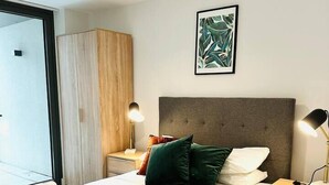 Una camera da letto moderna con un letto grande, lampade sui comodini, un'armadio in legno e un'opera d'arte appesa al muro.