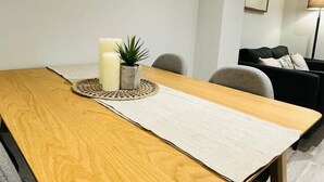 Un tavolo da pranzo in legno con un sottopiatti, due candele e una piccola pianta.