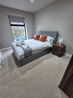 A bedroom with a bed, a nightstand, a lamp, and a window. - #22 Lux Apart balcony 11|Near NEC & BHX|for 4 (Birmingham)