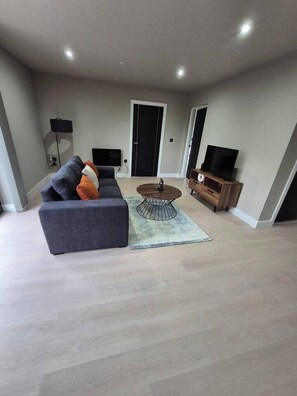 A modern living room with a sofa, coffee table, and entertainment unit. - #22 Lux Apart balcony 11|Near NEC & BHX|for 4 (Birmingham)