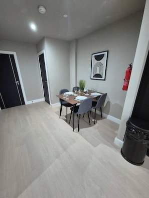 A dining area with a table set for four, chairs, a potted plant, and a framed artwork on the wall. - #22 Lux Apart balcony 11|Near NEC & BHX|for 4 (Birmingham)