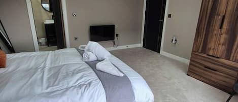 A bedroom with a bed, a wooden wardrobe, a television, and a mirror.