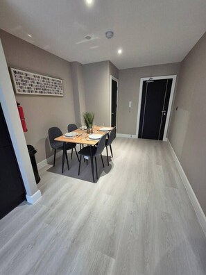 A dining area with a table and chairs, a potted plant, and a fire extinguisher on the wall. - #23 Lux Flatbalcony|10mins to ResortsWorldBHM|for4 (Birmingham)