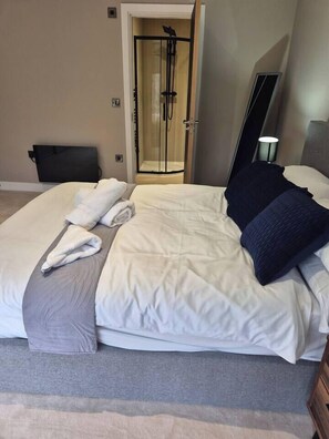 A neatly made bed with white linens and a grey throw blanket, a dark pillow, and a folded towel on the bed. - #23 Lux Flatbalcony|10mins to ResortsWorldBHM|for4 (Birmingham)