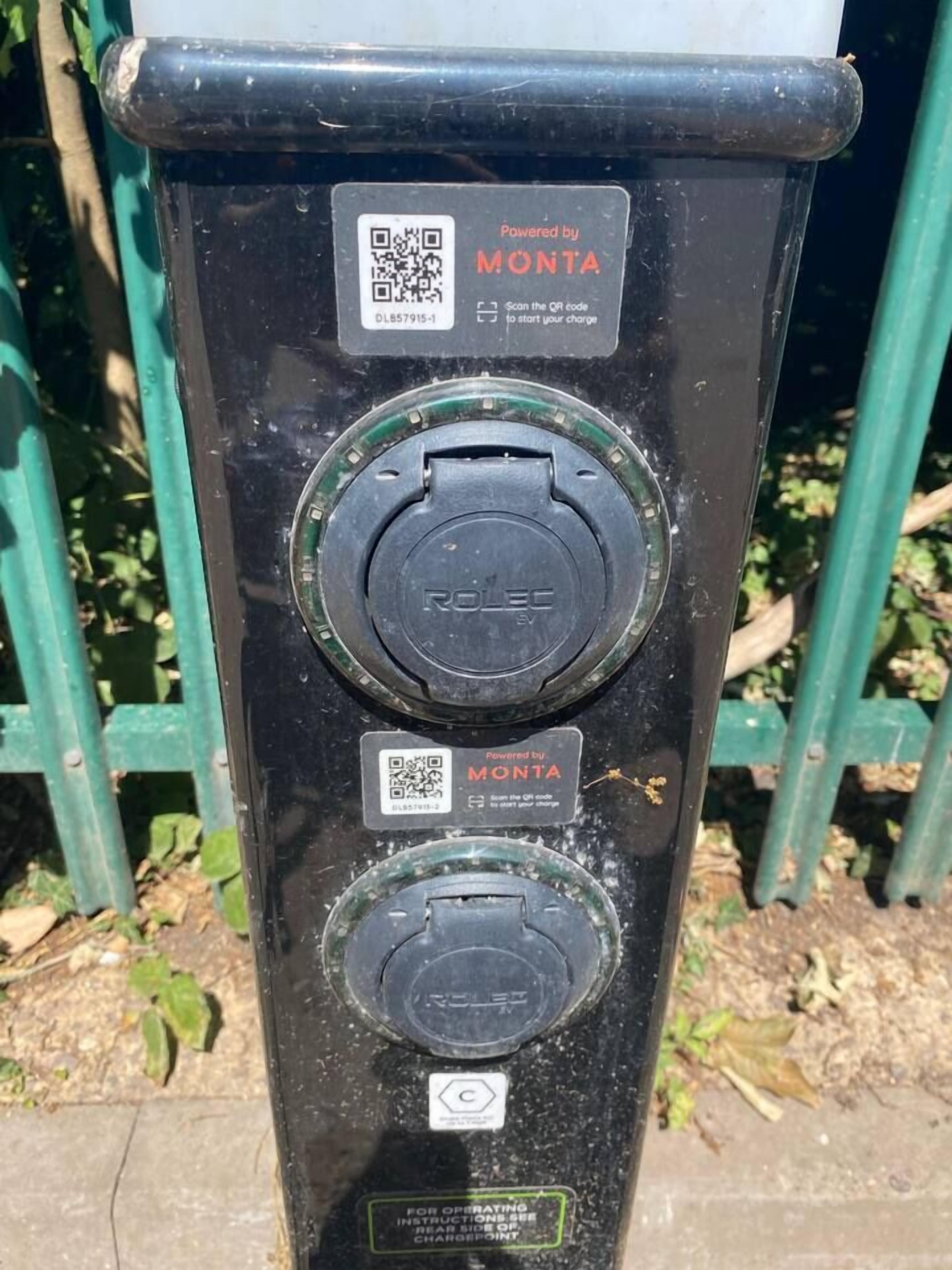 A black electric vehicle charging station with QR codes and a label indicating it is powered by MONTANA.