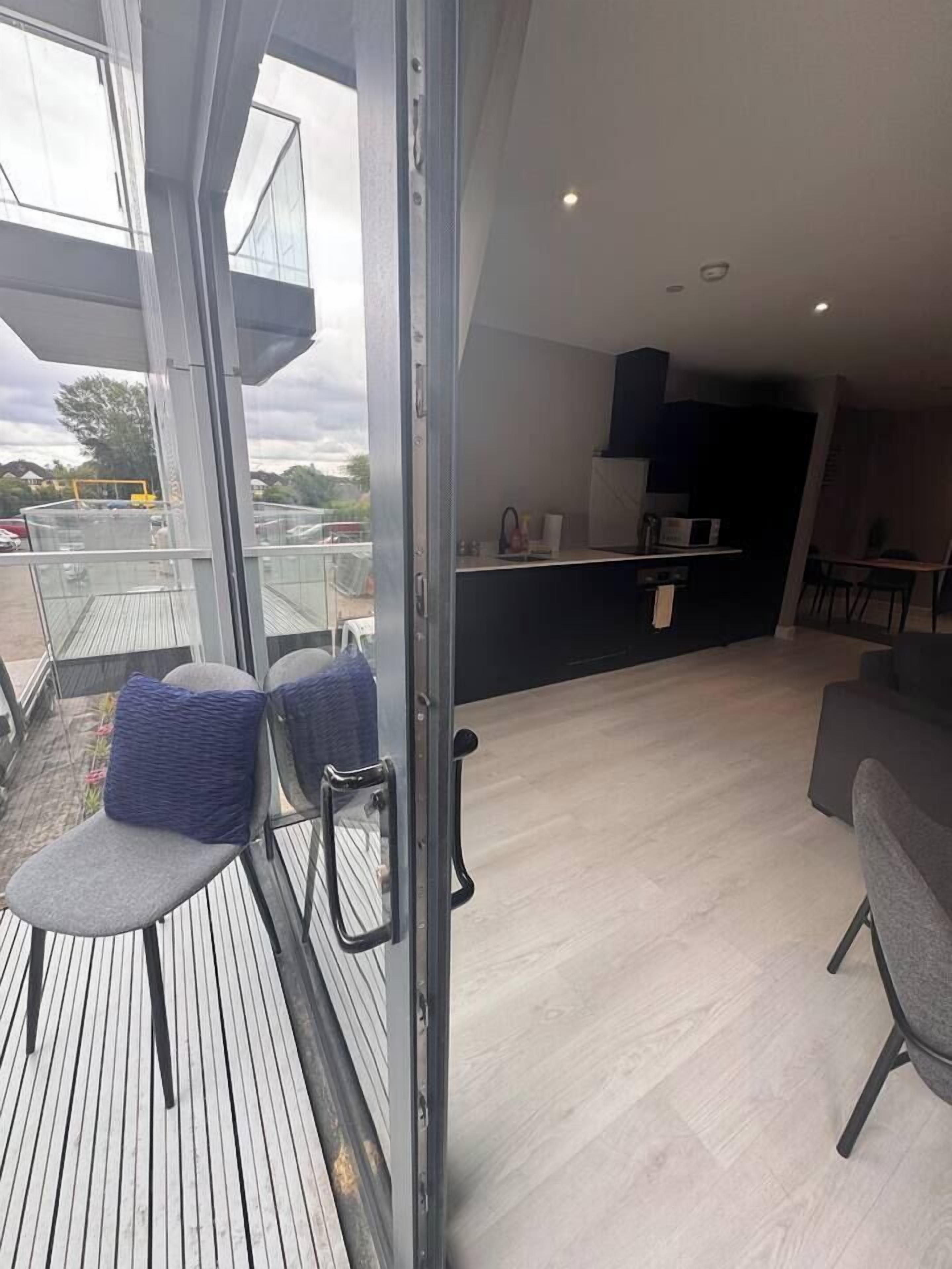 Et moderne interiør med balkon, siddeområde og et køkken.