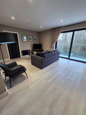 A modern living room with a sofa, a chair, a flat-screen TV, and a large window. - #23 Lux Flatbalcony|10mins to ResortsWorldBHM|for4 (Birmingham)