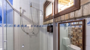 Un baño con cabina de ducha de vidrio, inodoro y lavamanos.