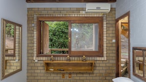 Un dormitorio con pared de ladrillo, ventana de madera, mesita de noche y cama.