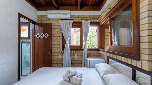Un dormitorio con cama, ventana con cortinas, aire acondicionado de pared y puerta de madera.