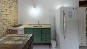 Una cocina compacta con estufa a gas, lavamanos y un refrigerador blanco.