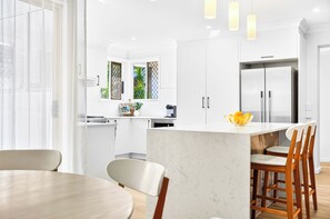 Una cocina moderna con armarios blancos, encimera de mármol y una isla integrada con taburetes de bar.