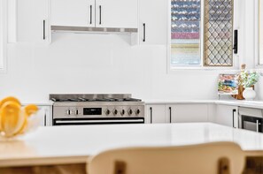 Una cocina moderna con armarios blancos, una estufa a gas y un ventanal con vistas decorativas.