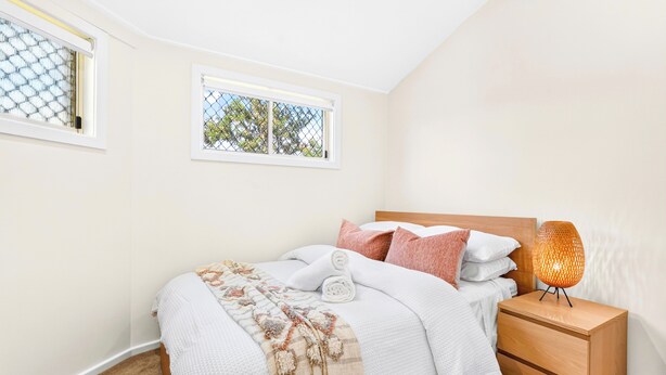 A bedroom with a bed, nightstand, and a window with a view of trees. - Zuri Luxury Coastal Staycation• 2 Min to Beach, Cafés & Lakefront (The Entrance)