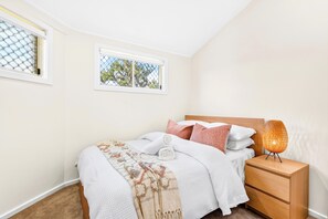 A bedroom with a bed, nightstand, and a window with a view of trees. - Zuri Luxury Coastal Staycation• 2 Min to Beach, Cafés & Lakefront (The Entrance)