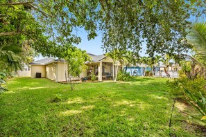A residential property with a well-maintained lawn, a covered patio area, and a house with a visible garage. - Right Direction Rentals Carlton Coastal Cottage (Fort Pierce)