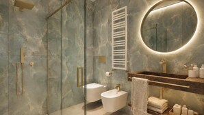 Ein modernes Badezimmer mit einer gläsernen Duschkabine, einem runden Spiegel mit integrierter Beleuchtung, einem Holzwaschtisch und einem weißen Waschbecken.