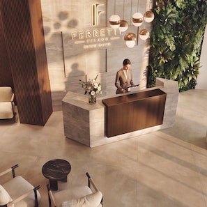 A reception desk with a modern design, a man standing behind it, and a plant wall to the right. - Ferretti Suite Hotel Al Duomo (Milan)