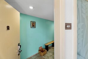 Ein Flur mit einer türkisfarbenen Wand, einer Holztür, einer Bank, einem Korb und einem Schild mit der Nummer 401.