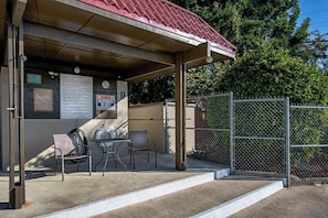 A covered outdoor seating area with a pool rules sign, a clock, and a fenced pool area. - Kona Mansions#B116 Mountain views, No Stairs, Heart of Town (Kailua Kona)