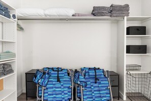 Un espacio de almacenamiento ordenado con estantes, toallas dobladas y un perchero con objetos doblados.