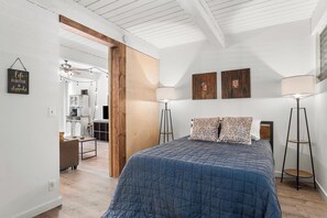 Ein Schlafzimmer mit einem Bett, zwei Wandlampen und einer Küche im Hintergrund.