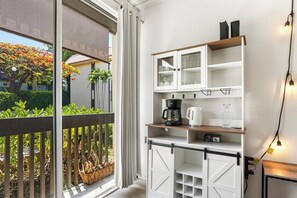 A modern kitchen with white cabinets, a coffee maker, and a kettle on the counter. - Kona Mansions#B116 Mountain views, No Stairs, Heart of Town (Kailua Kona)