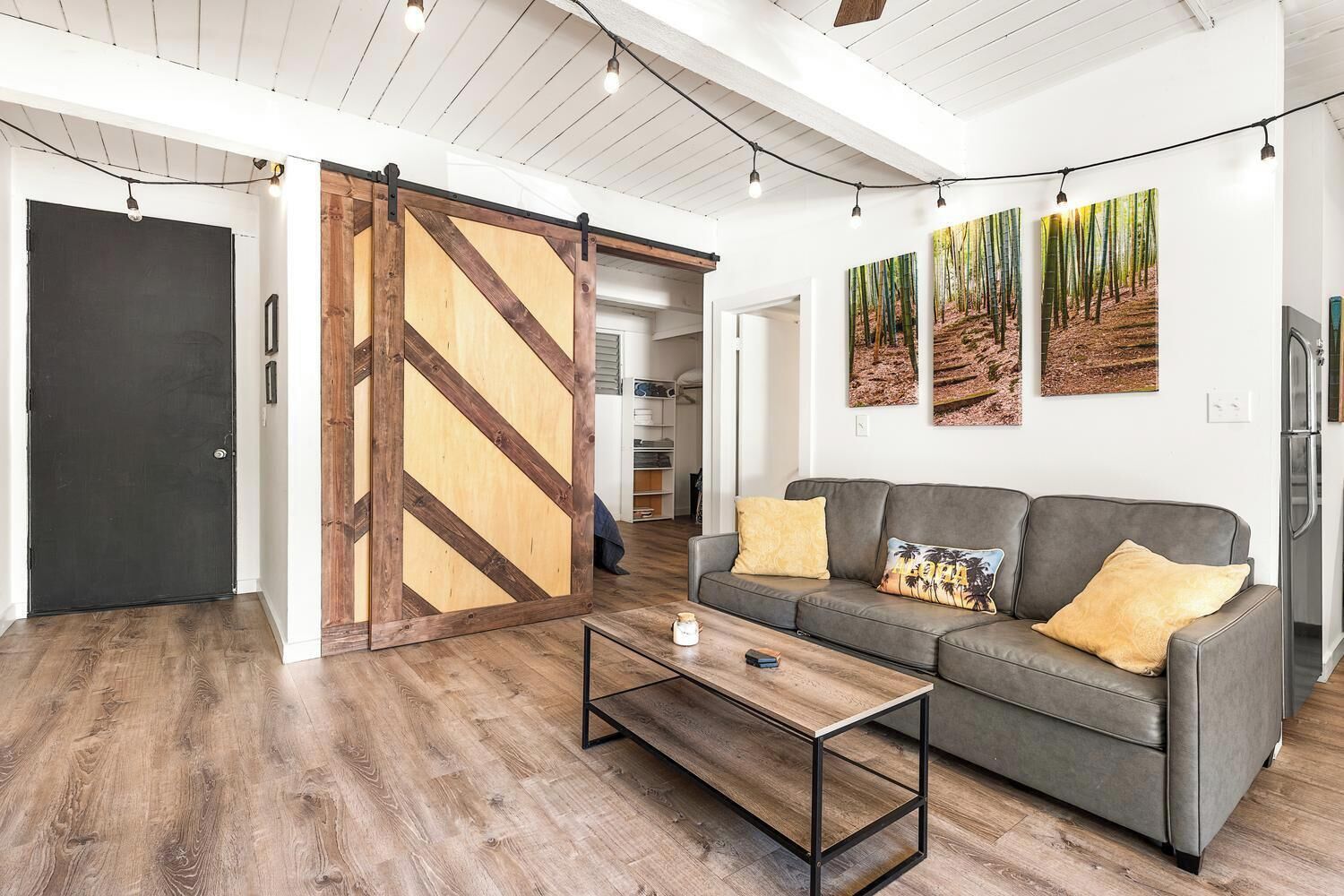 Ein modernes Wohnzimmer mit grauem Sofa, Holztisch und einer Schiebetür im Scheunenstil.