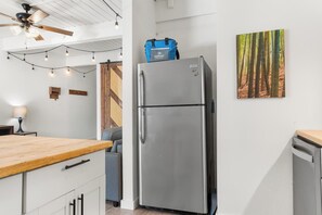 Una cuina moderna amb nevera d'acer inoxidable, taulell de fusta i ventilador de sostre.