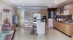 Une cuisine moderne dotée d’un îlot central, d’appareils électroménagers en acier inoxydable et d’un coin bar avec des tabourets.