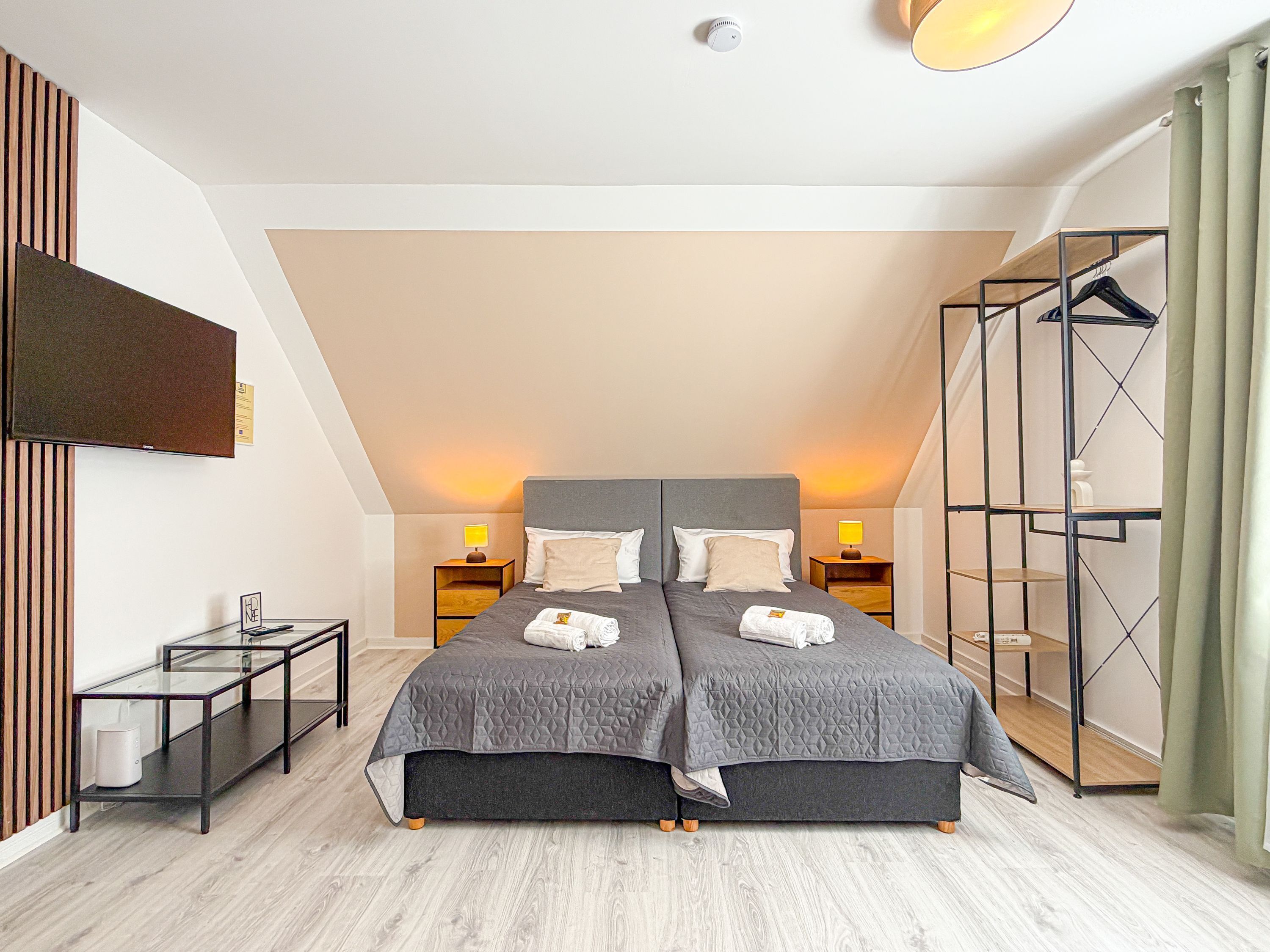 Ein Schlafzimmer mit einem großen Bett, zwei Nachttischen, einem Fernseher und einem Kleiderschrank.