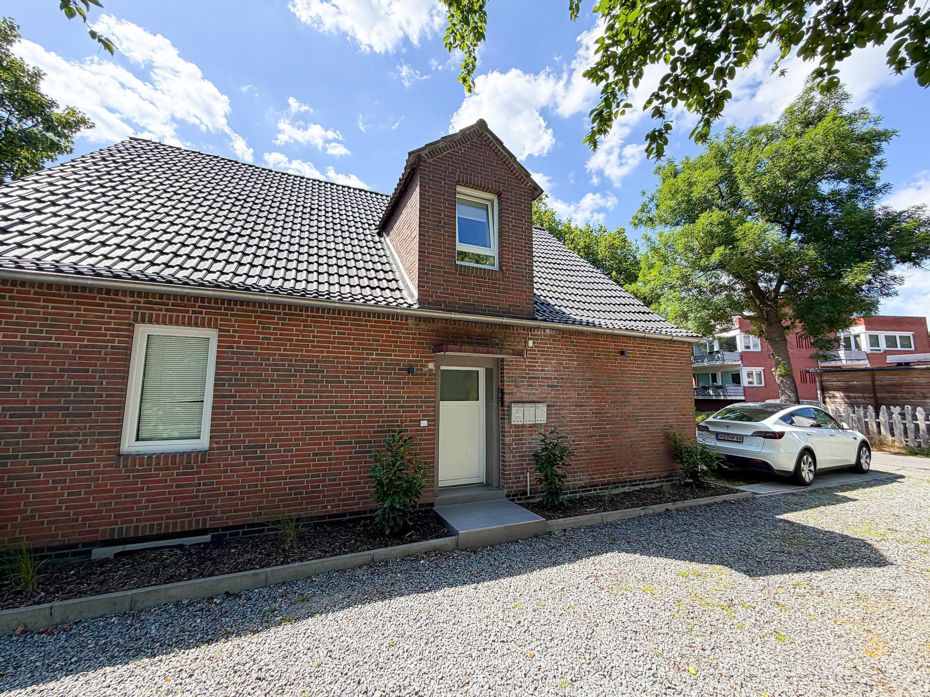 A brick house with a tiled roof, a small window, and a door.