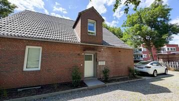 A brick house with a tiled roof, a small window, and a door.
