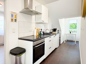 Una cocina moderna con armarios blancos, una campana extractora de acero inoxidable y una encimera negra.
