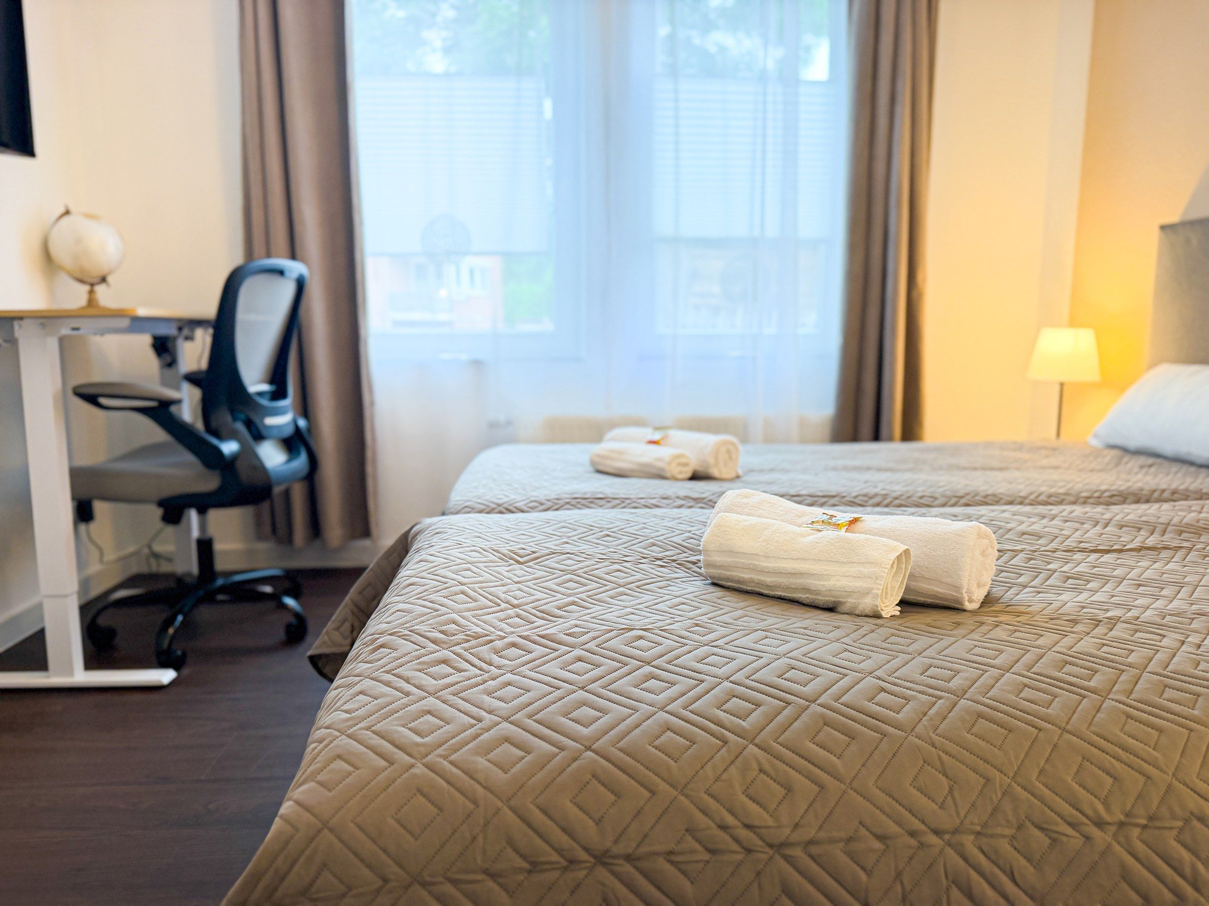 A hotel room with a bed, a desk, and a chair.