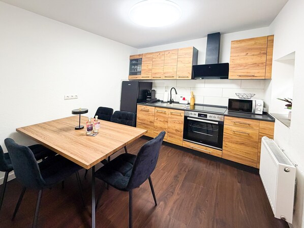 Una cocina moderna con armarios de madera, una mesa de comedor con sillas y un horno empotrado.