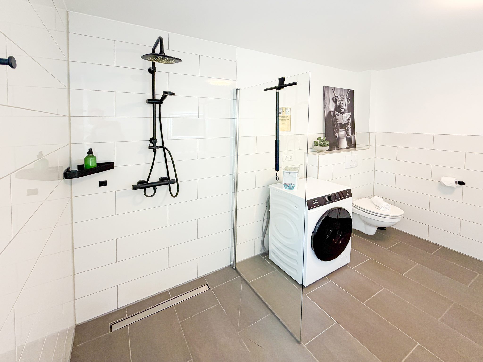 Ein modernes Badezimmer mit Dusche, Toilette und Waschmaschine.