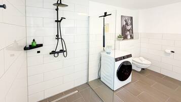 Ein modernes Badezimmer mit Dusche, Toilette und Waschmaschine.