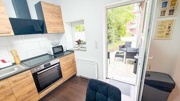 A modern kitchen with wooden cabinets, a built-in oven, and a microwave.