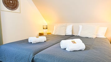 Quarto de hotel com uma cama grande, duas almofadas, uma mesa de cabeceira com abajur e uma obra de arte na parede.