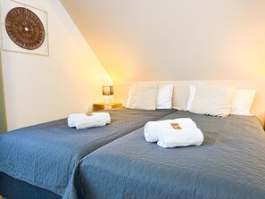 Una habitación de hotel con una cama grande, dos almohadas, una mesita de noche con una lámpara y una obra de arte en la pared.