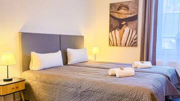 Habitación de hotel con una cama grande, dos mesitas de noche, una lámpara y un cuadro en la pared.