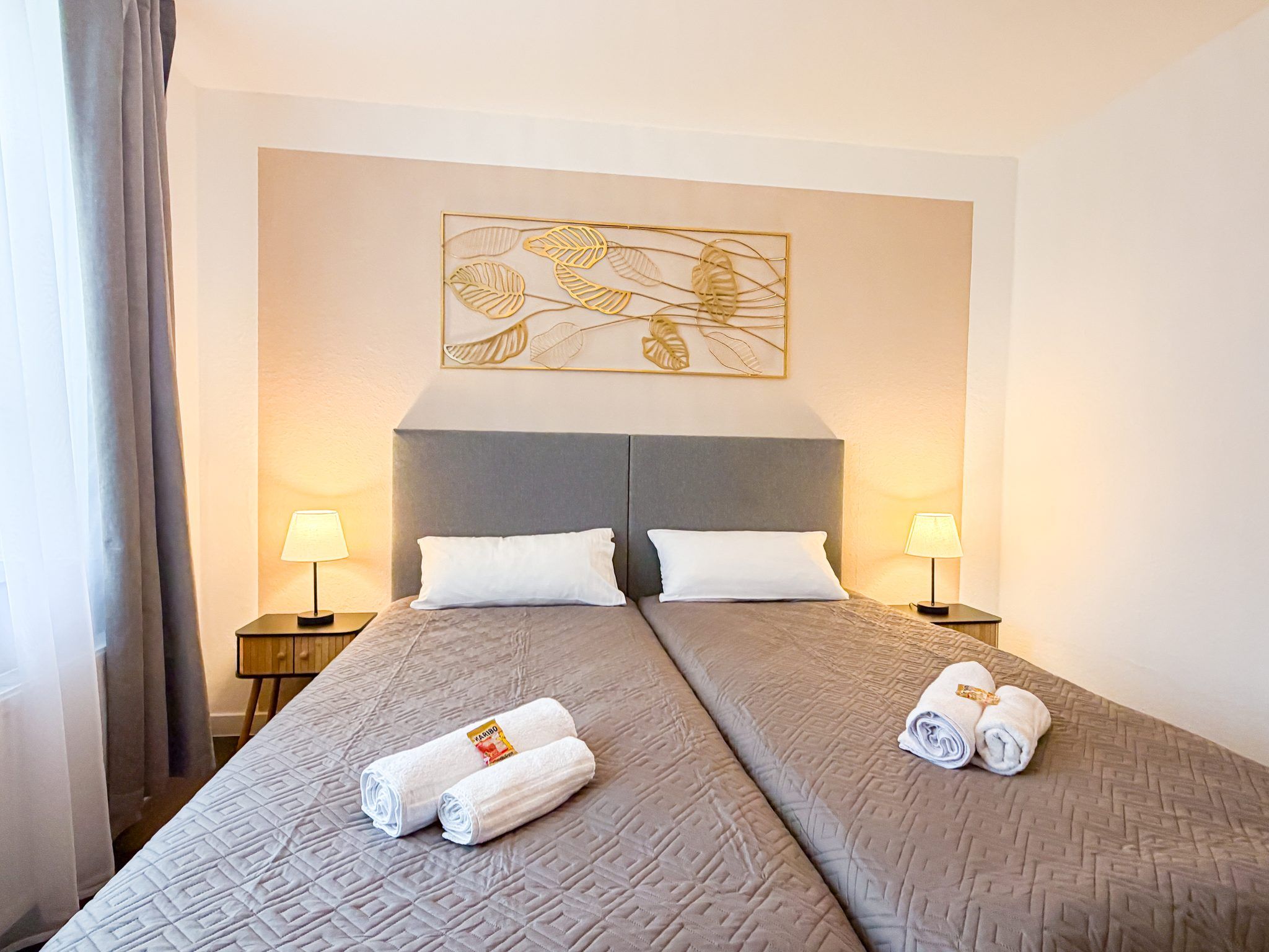 A hotel room with two beds, a large artwork above the headboard, and two bedside lamps.